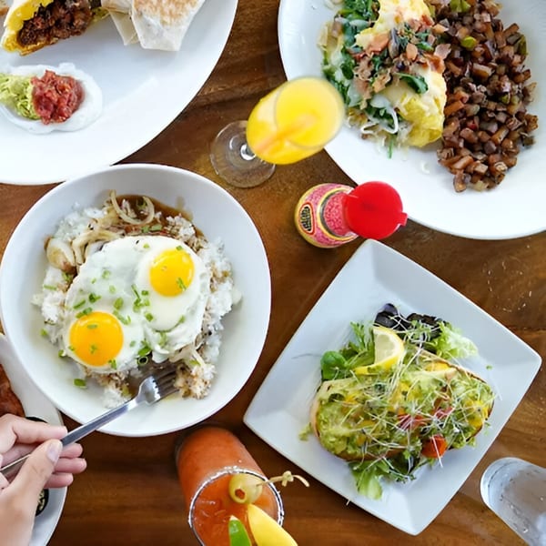 Overhead view of a table laden with various breakfast dishes, including wraps, eggs, and avocado toast.